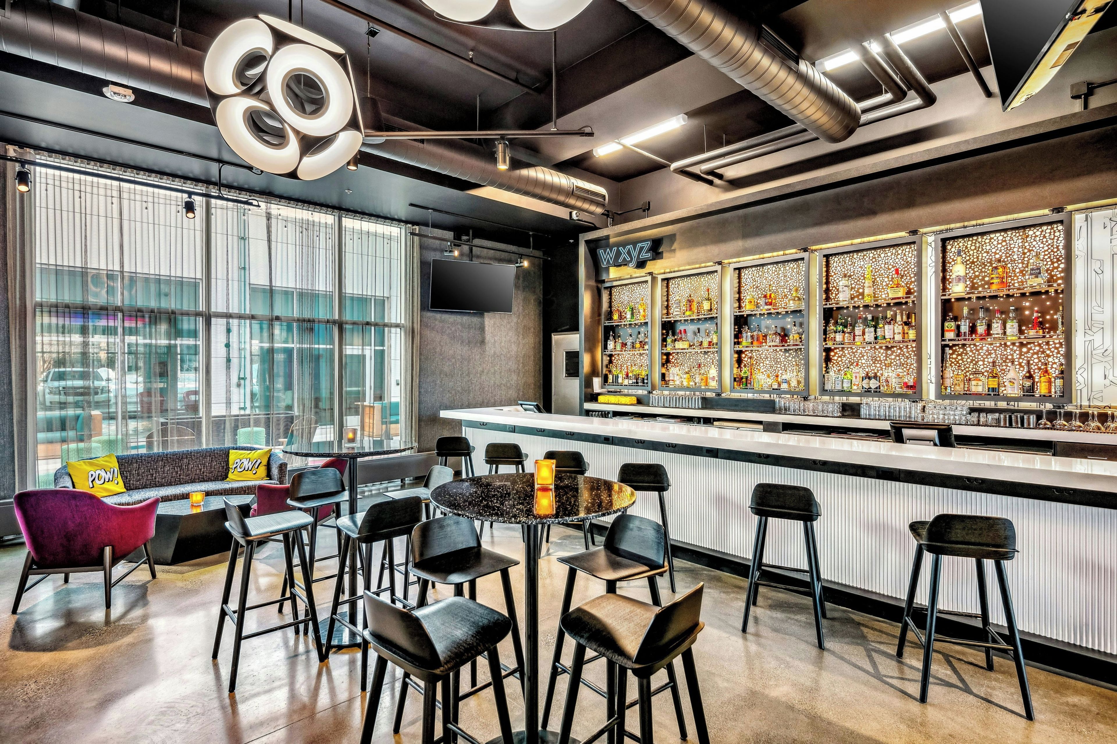 A modern bar area with a bar counter, seating, and a large display of liquor bottles.