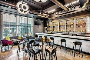 A modern bar area with a bar counter, seating, and a large display of liquor bottles. - Aloft by Marriott Anchorage (Anchorage)