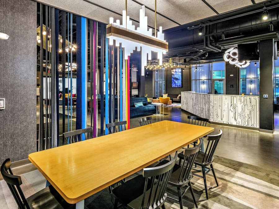 A modern interior with a long wooden table, black chairs, and a colorful vertical partition.