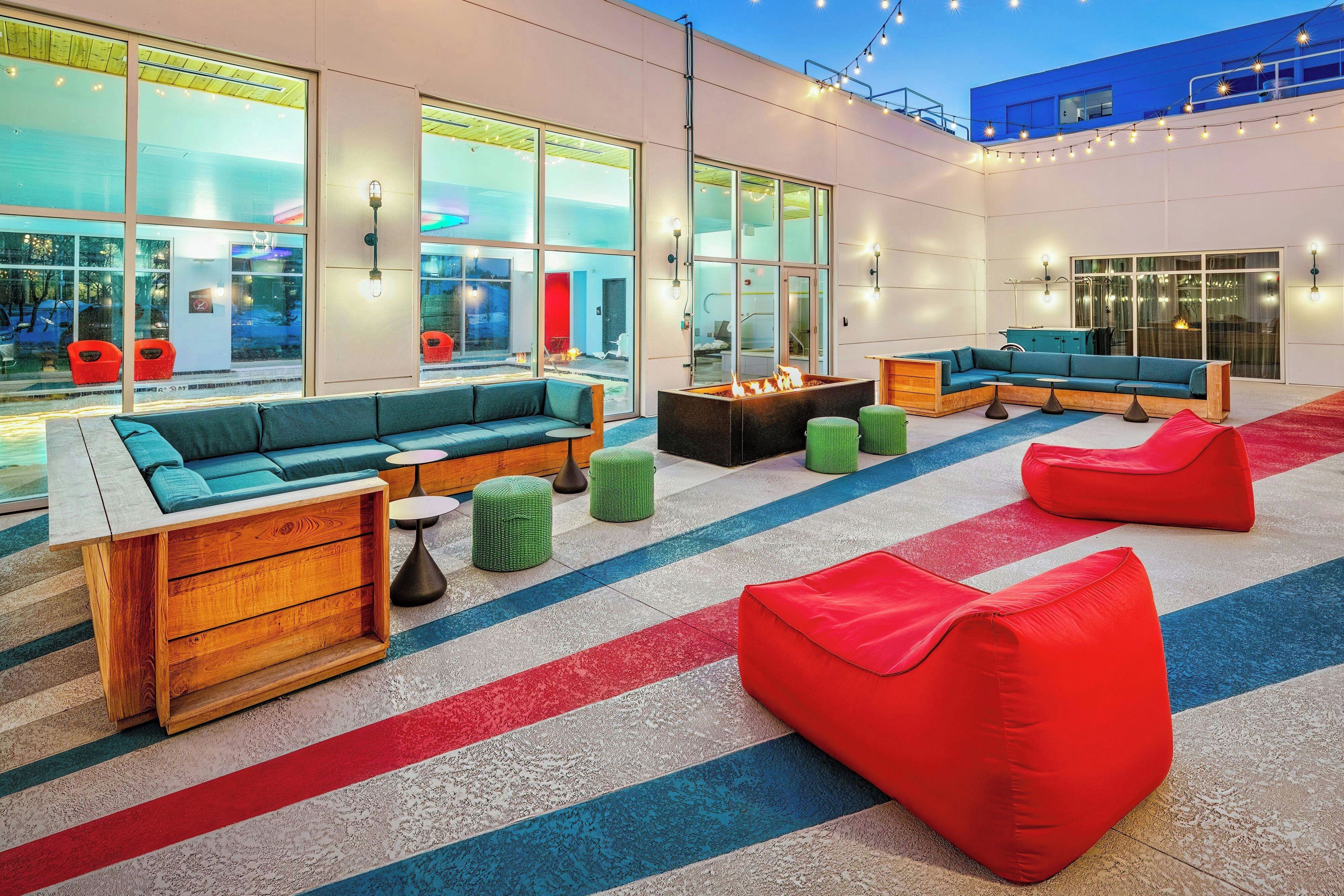 Un espace de détente extérieur moderne, aménagé avec des sièges confortables, un foyer et de grandes fenêtres offrant une vue panoramique.