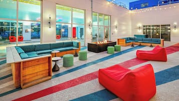 Un espace de détente extérieur moderne, aménagé avec des sièges confortables, un foyer et de grandes fenêtres offrant une vue panoramique.