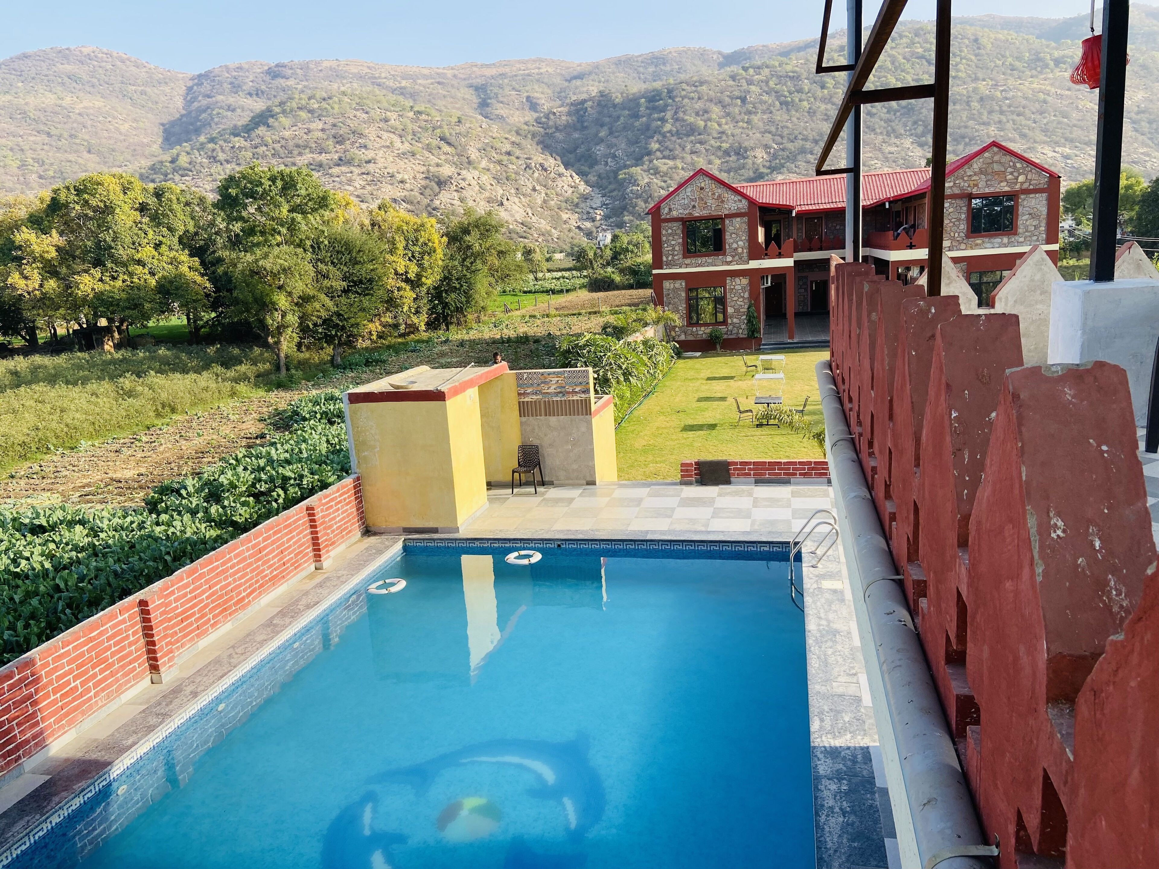 Una piscina con vistas a un paisaje montañoso y un edificio de techo rojo.