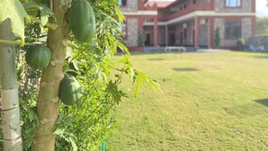 A building with a red roof and stone walls, surrounded by a well-maintained lawn. - Pushkar Retreat Resort (Pushkar)