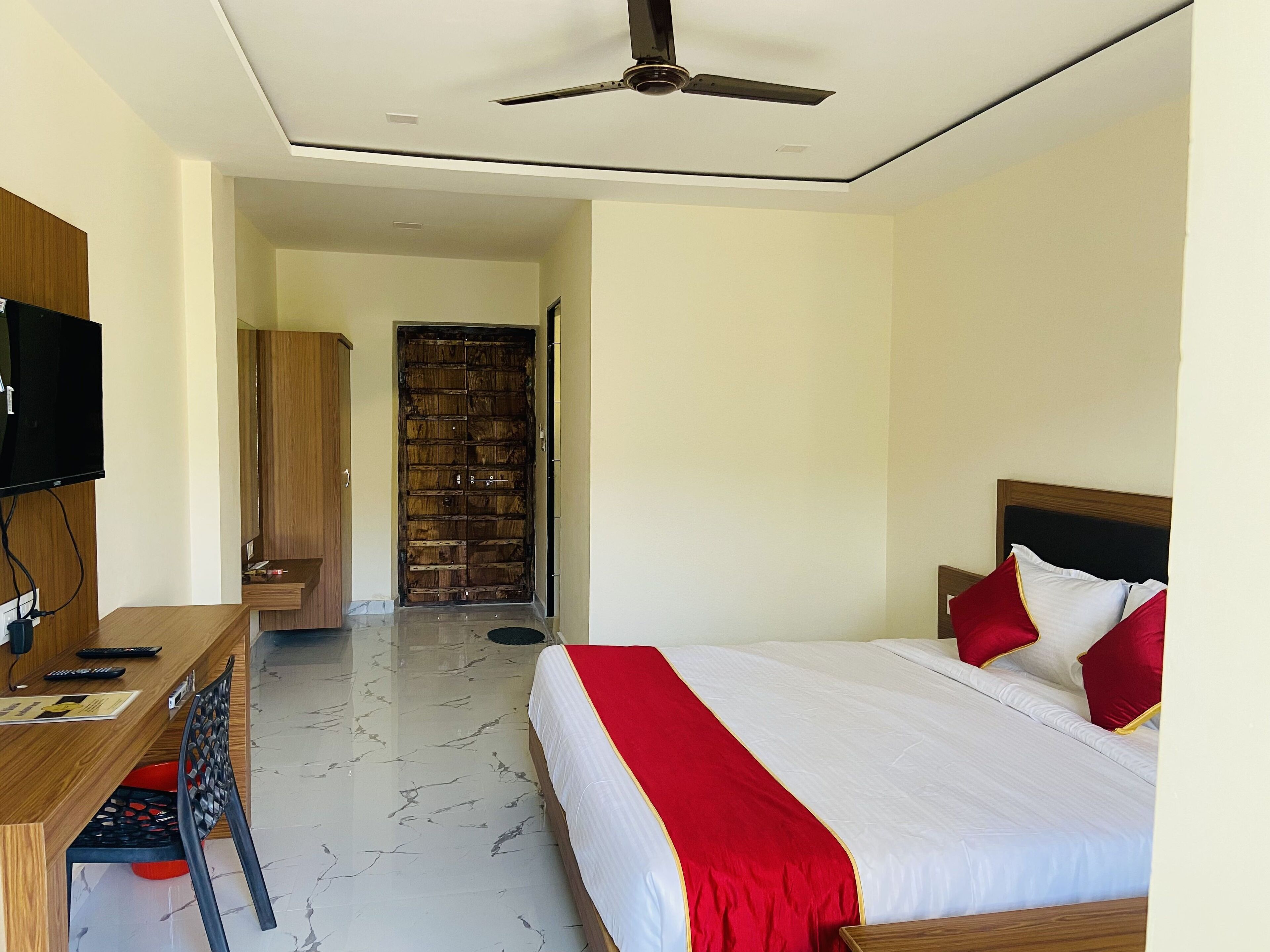 Une chambre d’hôtel comprenant un lit, un bureau avec une télévision, une armoire et une porte donnant sur une autre pièce.