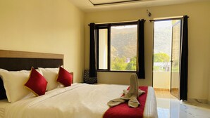 A hotel room with a large bed, a wooden headboard, and a view of the outdoors through a window. - Pushkar Retreat Resort (Pushkar)