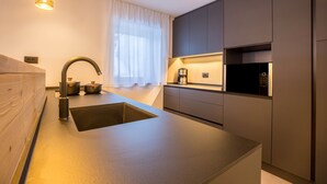 Una cocina moderna con un lavamanos integrado, electrodomésticos de acero inoxidable y una lámpara colgante.