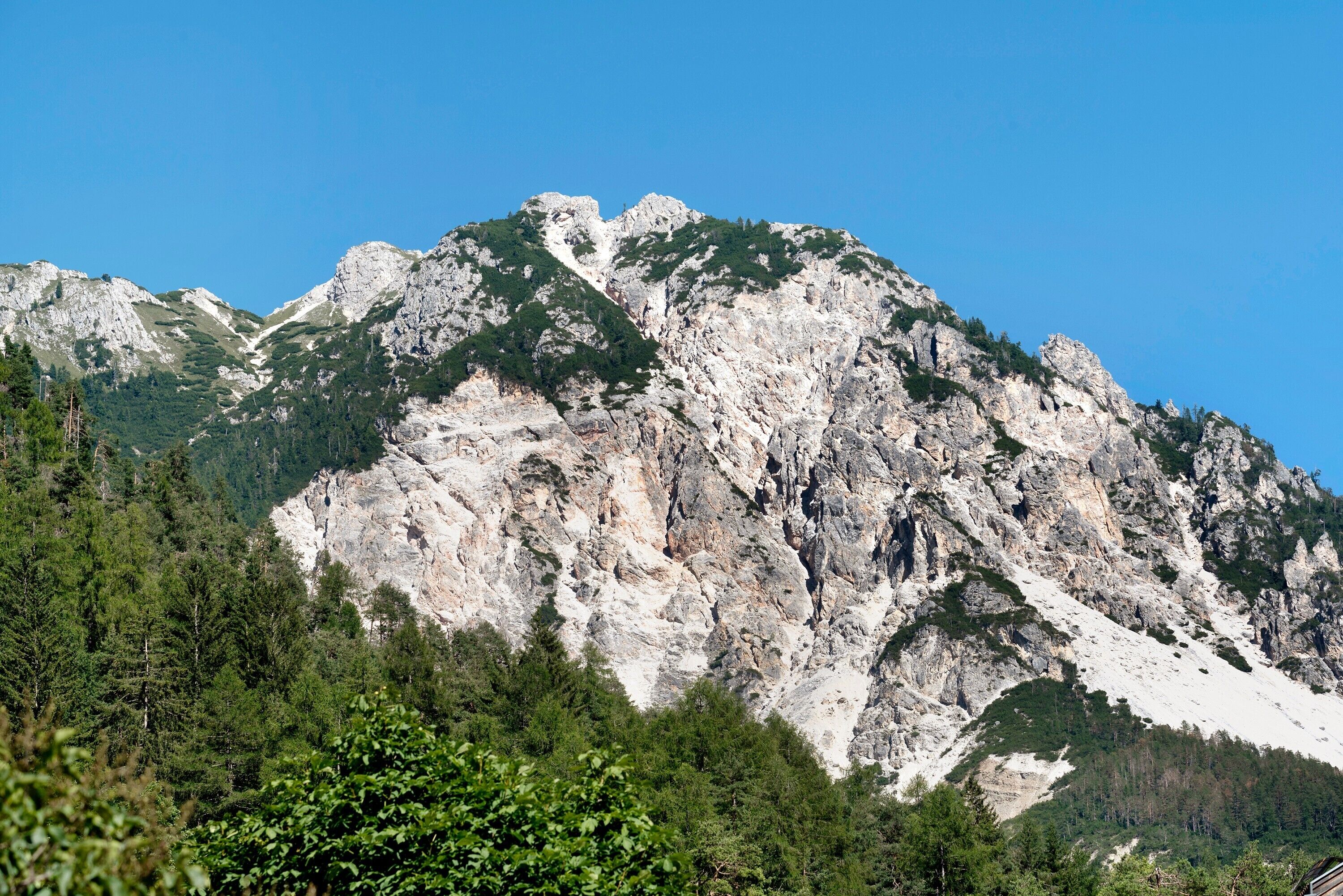 A mountain landscape with rocky cliffs and dense forest.