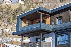 A modern multi-story building with balconies, large windows, and a view of a snowy landscape.