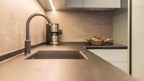 Een moderne keuken met een roestvrijstalen spoelbak, een koffiezetapparaat en een pan op het aanrecht.