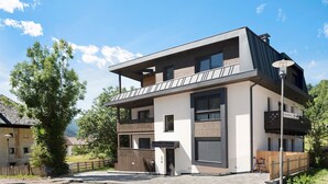 Een modern gebouw met twee verdiepingen, een balkon, grote ramen en een bord dat een restaurant aangeeft.