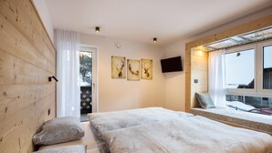 Een slaapkamer met twee bedden, een televisie en een raam met uitzicht.