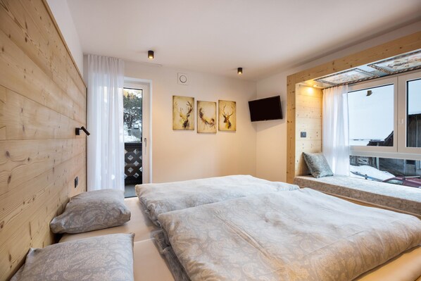A bedroom with two beds, a TV, and a window with a view.