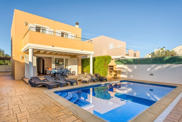 A modern house with a swimming pool, outdoor seating, and a covered patio.