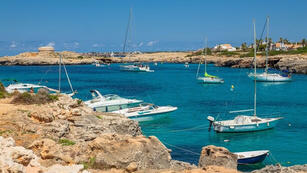 A coastal marina with boats docked, rocky terrain, and buildings in the background. - Villa "Lorena" with Pool, Garden & Wi-Fi (Ciutadella de Menorca)