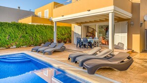 A swimming pool with lounge chairs, a covered patio, and a dining area with outdoor furniture. - Villa "Lorena" with Pool, Garden & Wi-Fi (Ciutadella de Menorca)