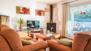 A modern living room with a fireplace, comfortable seating, a flat-screen TV, and artwork on the walls. - Villa "Lorena" with Pool, Garden & Wi-Fi (Ciutadella de Menorca)