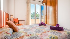 A hotel room with a bed, a chair, a desk, and a sliding glass door to the balcony. - Villa "Lorena" with Pool, Garden & Wi-Fi (Ciutadella de Menorca)