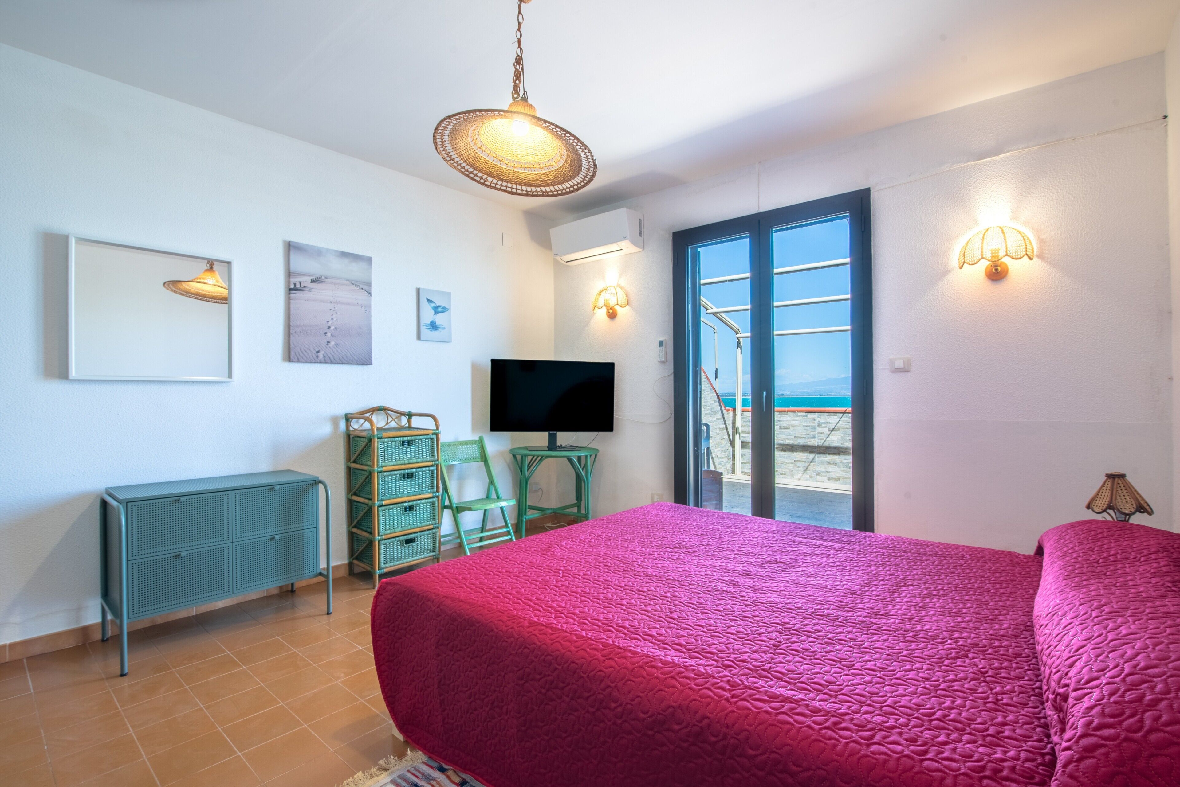 Una camera da letto con un letto grande, una televisione, un comò e un balcone con vista.
