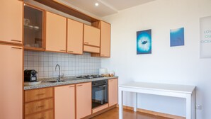 Una cocina con armarios de madera, una encimera, un fregadero, una estufa y una mesa.