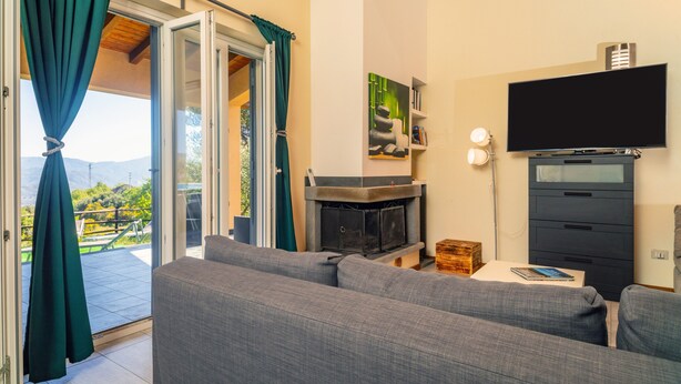 Un salon comprenant un canapé, un téléviseur à écran plat, une cheminée et une porte-fenêtre coulissante donnant sur un balcon.
