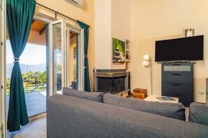 Un salon comprenant un canapé, un téléviseur à écran plat, une cheminée et une porte-fenêtre coulissante donnant sur un balcon.