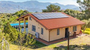 Une maison dotée d’un toit équipé de panneaux solaires, d’un porche abrité et offrant une vue sur les montagnes.