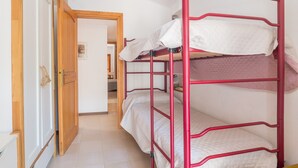 Un lit superposé avec une structure rouge, une porte en bois et un sol carrelé.