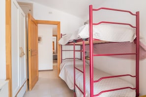 Een stapelbed met een rood frame, een houten deur en een betegelde vloer.