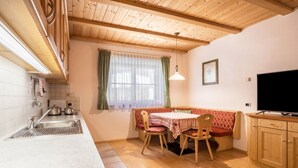 Una cucina con lavello, fornello e pensili. C'è un'area pranzo con tavolo e sedie.