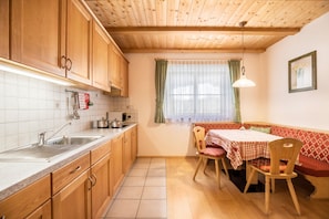 A kitchen with wooden cabinets, a sink, and a dining area with a table and chairs.
