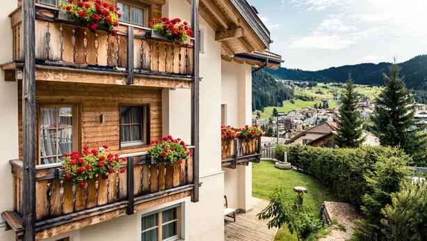 A multi-story building with wooden balconies, each adorned with flower boxes. - Apartment 'Lisüra Boè' with Mountain View and Wi-Fi (Corvara)