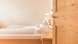 A wooden door leading to a bedroom with a bed and a nightstand. - Apartment 'Lisüra Boè' with Mountain View and Wi-Fi (Corvara)
