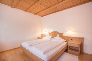 Ein Schlafzimmer mit einem Holzbett, zwei Nachttischen mit Lampen und einer Holzbalkendecke.