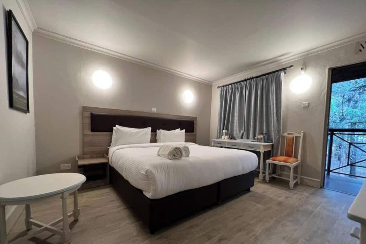 A hotel room with a large bed, bedside tables, a small desk, and a chair.