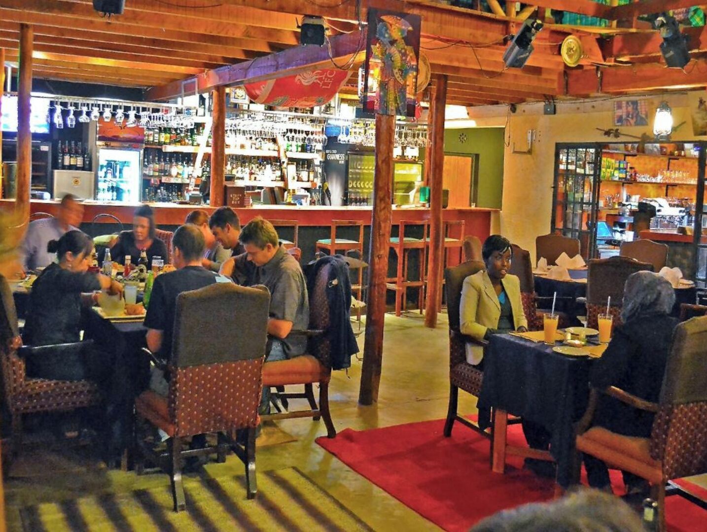 A restaurant with wooden furniture and a bar area in the background.