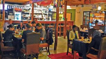 A restaurant with wooden furniture and a bar area in the background.