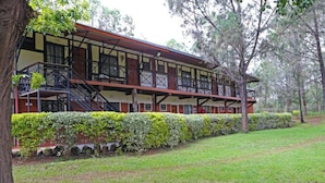 A two-story building with a balcony, surrounded by a well-maintained hedge and trees. - Kongoni Camp (Nanyuki)