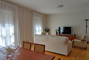 A living room with a sofa, TV, and dining table.