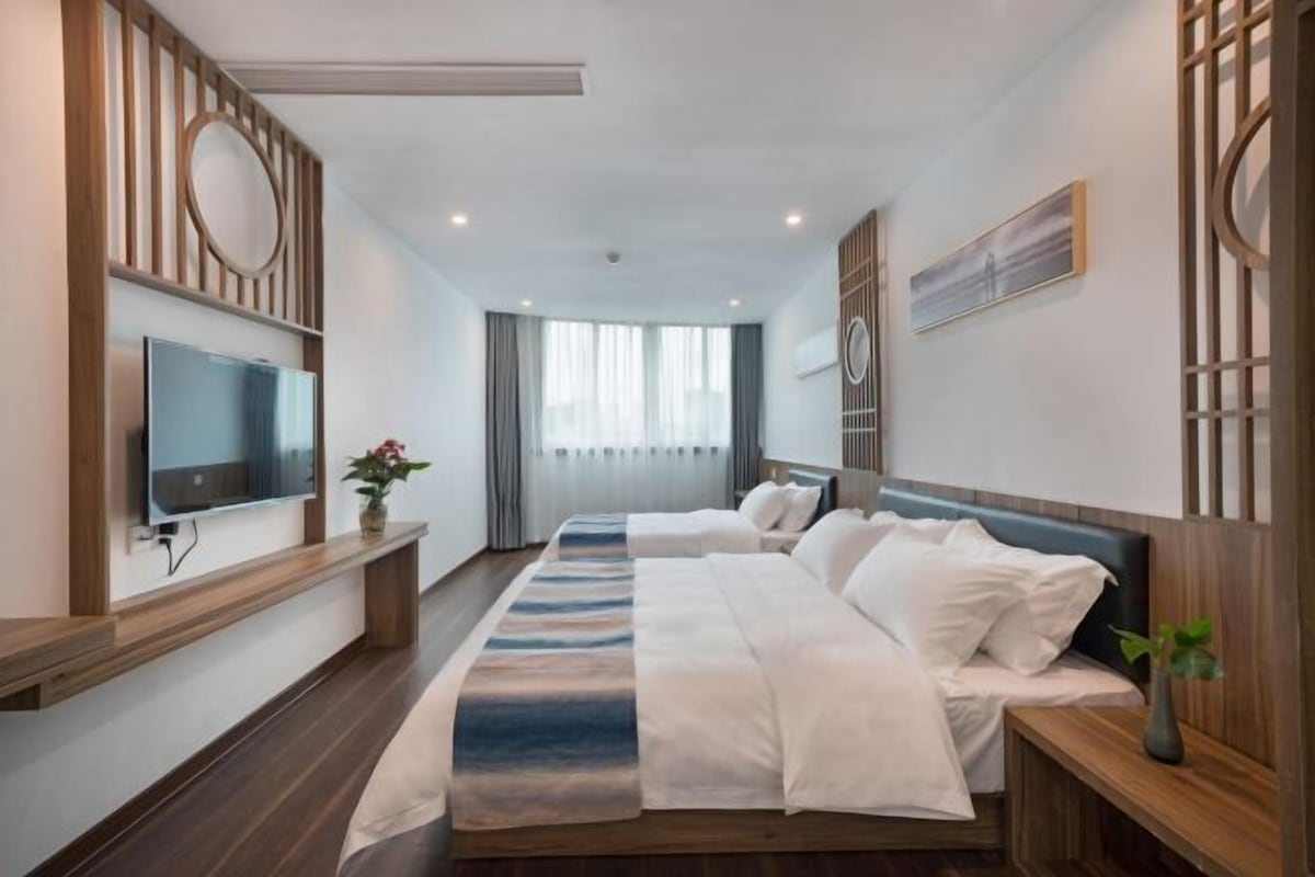 A modern hotel room with a large bed, a TV, and a view of the city.
