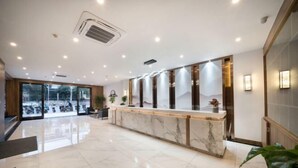 A hotel reception area with a marble counter, large windows, and a clean, modern design. - Jiu Jian Tang Bo City Hotel (Ningde)