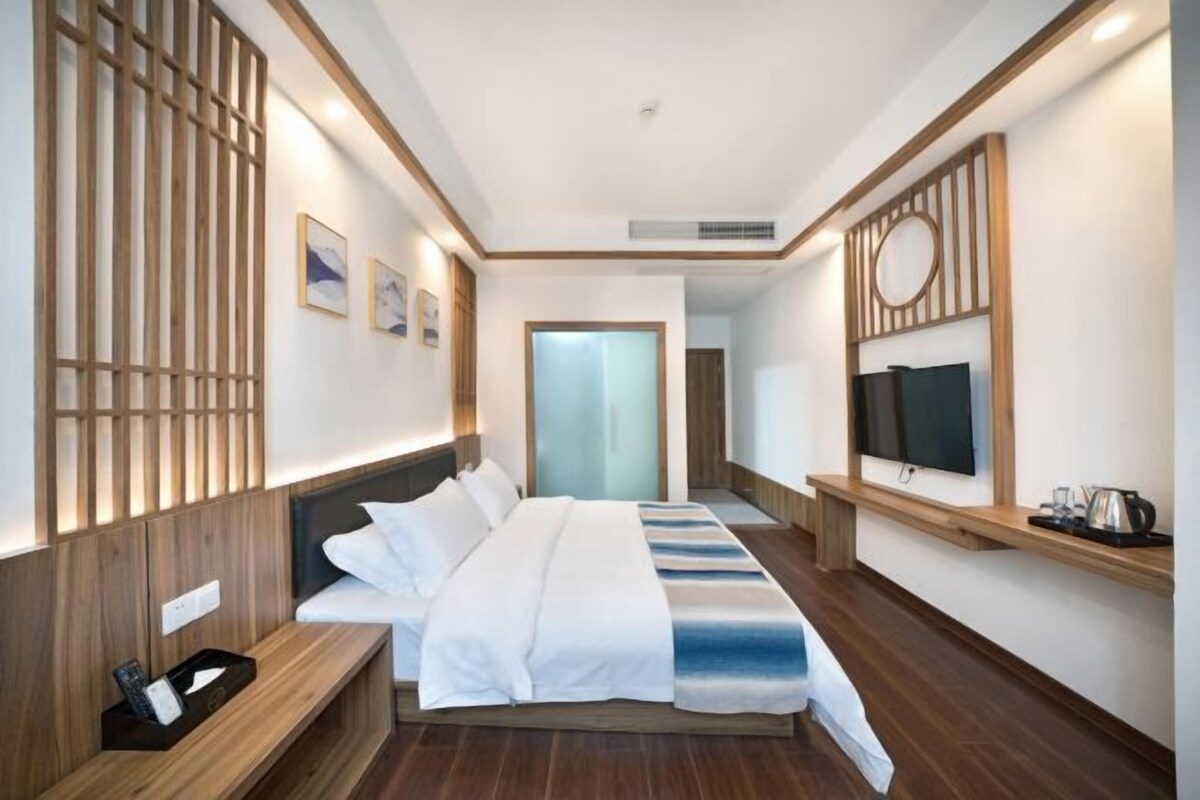A modern hotel room with a large bed, wooden paneling, a television, and a coffee maker.