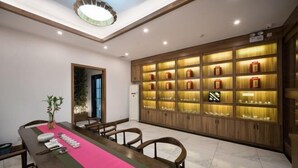 A conference room with a long table, chairs, a pink table runner, and a wall of illuminated cabinets. - Jiu Jian Tang Bo City Hotel (Ningde)