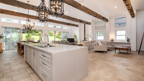 A spacious kitchen with a large island, a dining area with chairs, a sofa, and a TV. There are large windows and a view of the outdoors. - Pet Friendly - Chateau Rouge - Provincial Home Red Hill (Red Hill)