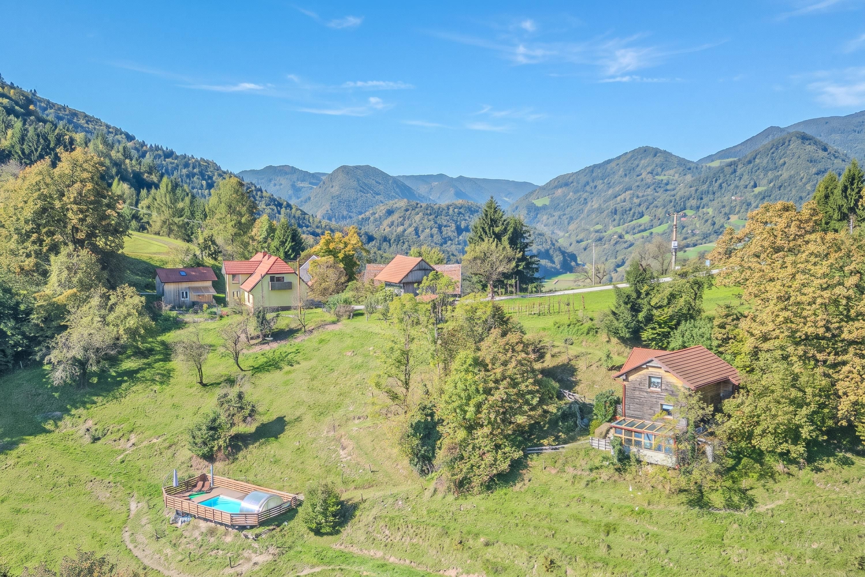 A rural landscape with houses surrounded by greenery and mountains.