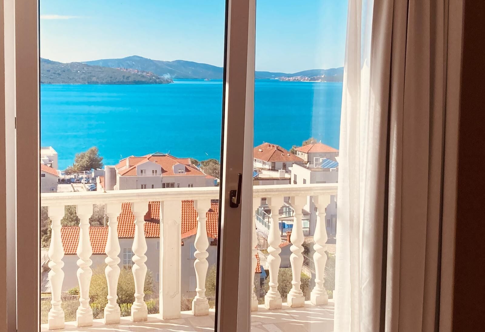 A balcony with a view of a coastal town and a large body of water.