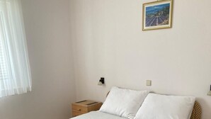 Un dormitorio con cama, mesita de noche, lámpara y un cuadro en la pared.