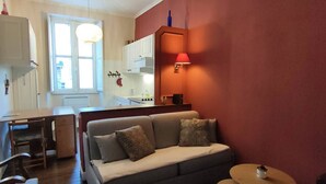 A modern living room with a grey sofa, a small round table, and a kitchen in the background. - 4-person Apartment near Cable Cars in Cauterets (Cauterets)