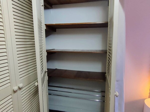 A closet with multiple shelves and drawers, likely used for storage.