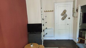 A compact room with a television, two small tables, a door with a decorative item, and a coat rack. - 4-person Apartment near Cable Cars in Cauterets (Cauterets)