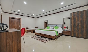A modern hotel room with a large bed, a desk, a red chair, and a wardrobe. - Treebo Paradise Premium Rasulgarh (Bhubaneshwar)